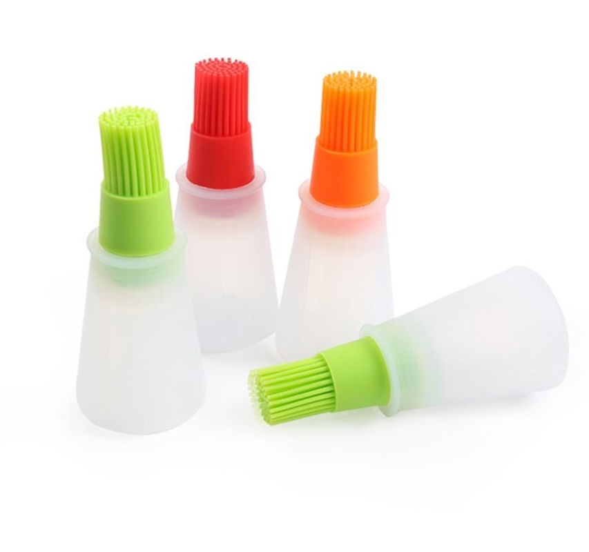 O BBQ do produto comestível utiliza ferramentas a garrafa branca do óleo de silicone com escova colorida