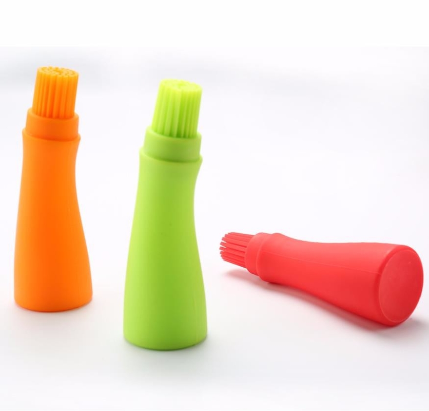 O assado do produto comestível utiliza ferramentas a garrafa branca do óleo de silicone com escova colorida